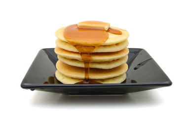 Plate of pancakes with maple syrup topped on white background