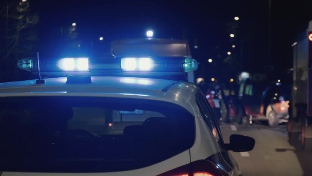 An accident on the highway in a major resort town. A team of ambulance paramedics and a fire truck rescue people. 911. Bright lights, flashing lights and sirens of a police patrol car. Car Crash