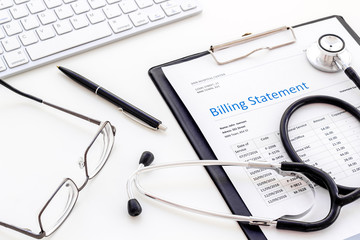 phonendoscope, billing statement and keyboard on work desk of doctor in hospital white background