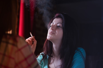 Obraz premium Young woman smoking cigarette in a cafe