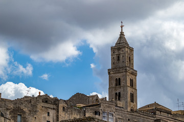 Fototapeta na wymiar Summer blue sky and church roof with religious cross, view of ancient town of Matera, the Sassi di Matera, Basilicata, Southern Italy, cloudy summer August day