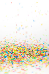 Colored confetti flying on white background
