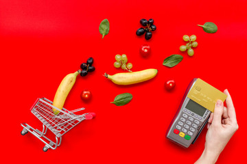 making purchase products online with card machine, fruits and mini trolley on office desk...