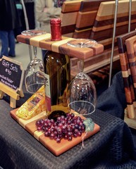 Bottle of wine, cheese, grapes, wine glasses, and wood cutting board 