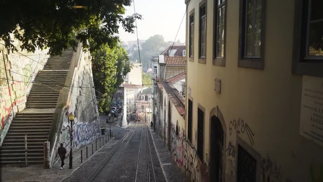 Tram moving on narrow old poor street view through tram window on ancient buildings wall with graffity and pedestrian descending on cobblestone pavement