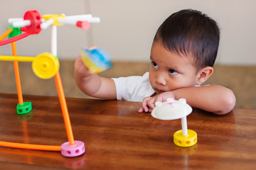 A moody child playing alone with learning toys on a table and expressing anti social behavior.