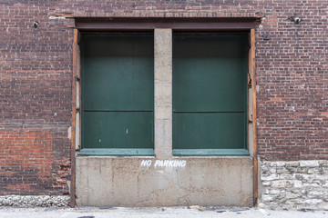 Fototapeta na wymiar Two green delivery doors on a loading dock of an abandoned red brick warehouse