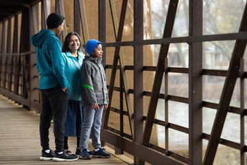 Obraz na płótnie Canvas Hispanic Woman And Sons Look Out Over River From Bridge
