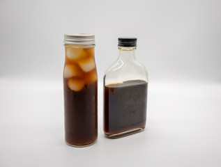 Cold Brew Coffee in glass bottle with black cap and cube ice in cylinder glass bottle isolated on white