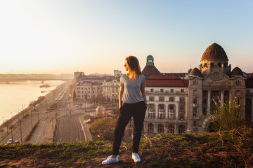 Beautiful woman standing opposite famous facade and entrance to Hotel Gellert on banks of Danube in...