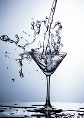 Water Splash Photography. Clear Wineglass With Burst of Water Splashes In Motion Against White Background.