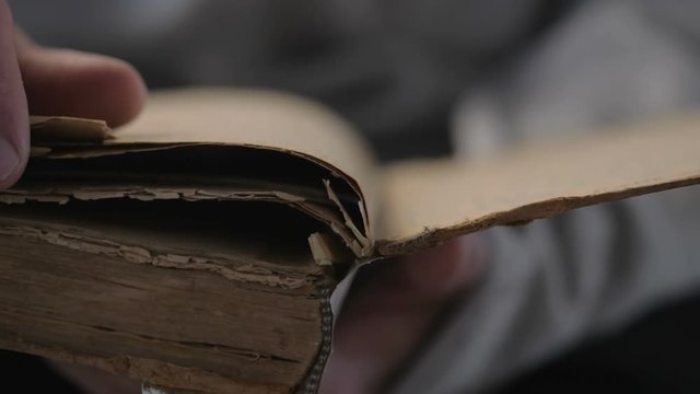 Hand and old book. A man's hand holds a book and read.  The hands are turning the pages of a very old book