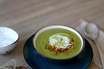 Creamy vegetable soup with kale, cabbage, celery and millet, decorated with olive oil, yoghurt sauce and chilli flakes. Selective focus.