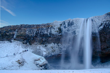 Fototapeta na wymiar Iceland waterfall seljalandsfoss frozen in winter with blue sky. 