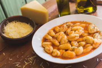 Gnocchi bolognese, cheese and olive oil on a rustic table
