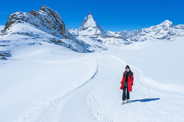 Fototapeta na wymiar Young woman tourists in the snow with the Matterhorn Mountain background, Zermatt, Switzerland.