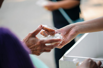 The hands of the rich are giving food to the poor and hungry.