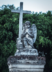 Fototapeta na wymiar Grave with a cherub and a cross made of marble