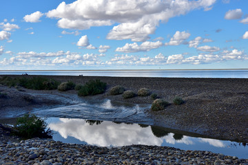 cielo azul con nubes blancas reflejadas en la laguna con mar calmo de fondo