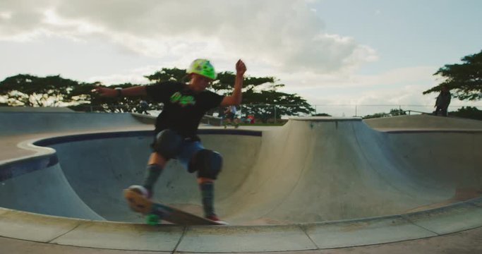Young skateboarder grinding the coping in a pool bowl, extreme shredder skateboarder kid in skatepark, slow motion
