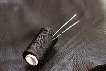 skein of thread with needle on black leather