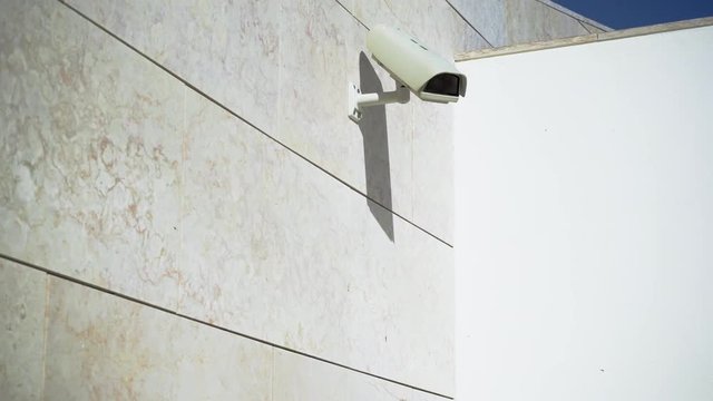 Modern security camera placed on grey wall of building