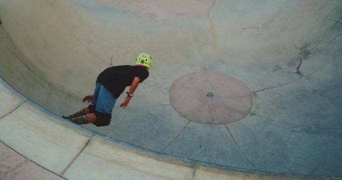 Young skateboarder kid riding in a pool bowl, extreme skateboarder boy, slow motion