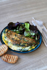 Frittata with chicory and cheese, served with oakleaf lettuce salad and toasted bread. Selective focus.