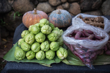 Fresh green chayote, purple yams, pumpkin and ginger on banana leaf at stall vegetable market.