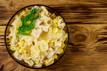Festive salad with chicken breast, sweet corn, canned pineapple, cheese and mayonnaise on wooden table