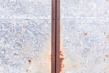 old detailed aged vintage rusty red brown textured zinc alloy metal sheet exterior fence door used in construction industry as warehouse building material. Good for background, backdrop, wallpaper