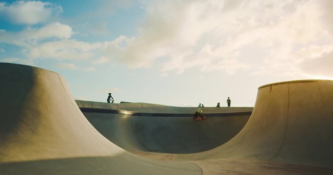 Skateboarder kid flying through the air in skate park at sunset, extreme skateboarding kid jumping high, young skateboarding shredder in slow motion