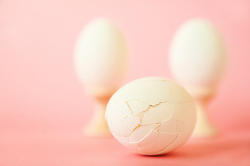 Egg and feathers on a pink background close-up and copy space. Easter concept with egg and feathers.