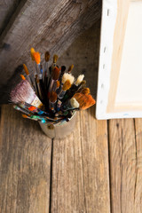 bundle of  paintbrush at tin can, artist canvas, rusty wooden