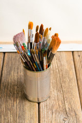 bundle of  paintbrush at tin can, artist canvas, rusty wooden