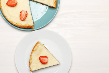 Classic cheesecake with strawberries on a white background. A piece on a plate. Top view.