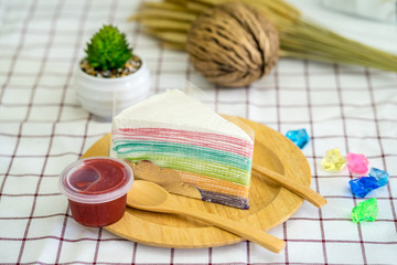 Fototapeta na wymiar Rainbow crepe cake with strawberry jam on wooden plate