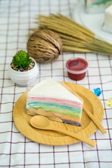 Rainbow crepe cake with strawberry jam on wooden plate