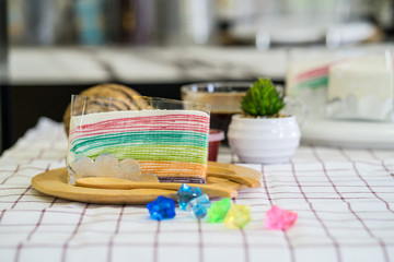 Rainbow crepe cake with strawberry jam on wooden plate