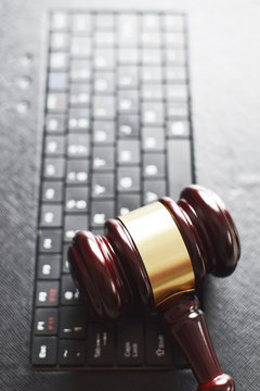 Wooden judge gavel on keyboard laptop computer. Concept of online auction, legal system, law and technology.