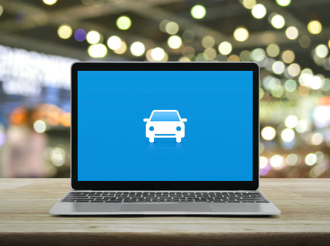 Taxi car flat icon with modern laptop computer on wooden table over blur light and shadow of shopping mall, Business transportation service online concept