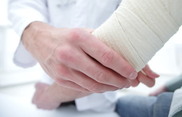Fototapeta na wymiar Orthopedist applying bandage onto patient's hand in clinic