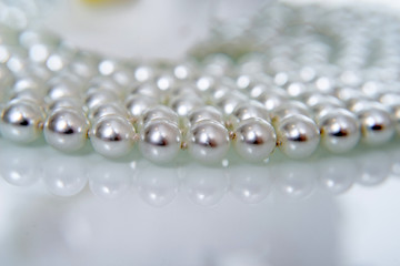 A necklace of pearls lying on white glass 