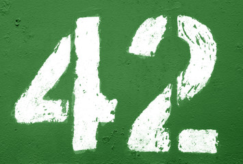 Number 42 in stencil on rusty metal wall in green tone.