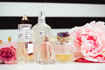 Bottles of perfume with flowers on light background