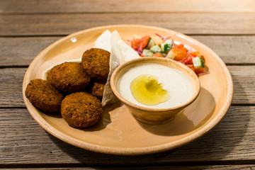 falafel with salad and sauce on a wooden table