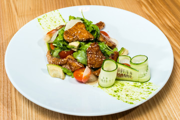 salad of fresh cucumbers and tomatoes fried meat on a wooden table