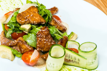 salad of fresh cucumbers and tomatoes fried meat on a wooden table