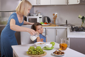  in the kitchen. mother scolding a child. a child refuses to eat, mom makes daughter eat healthy. mom and daughter are having Breakfast, the baby won't eat. quarrels, conflicts in the family