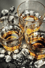 Whiskey and ice on rustic wood background